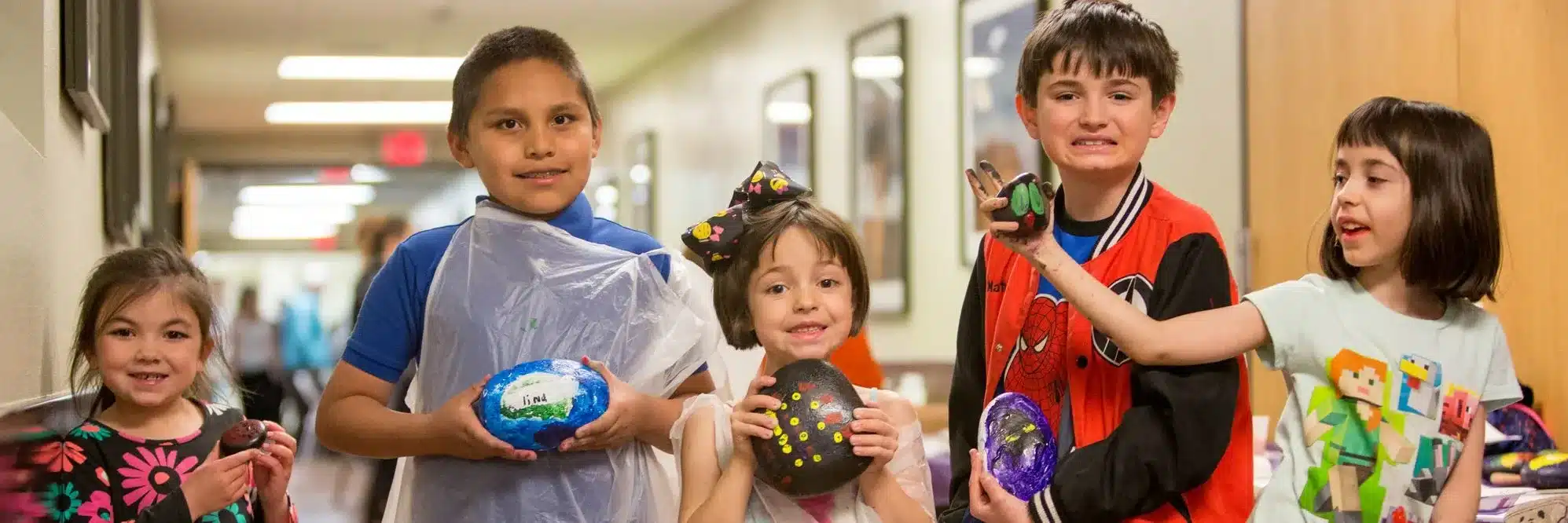 Children holding "Courage" stone paintings